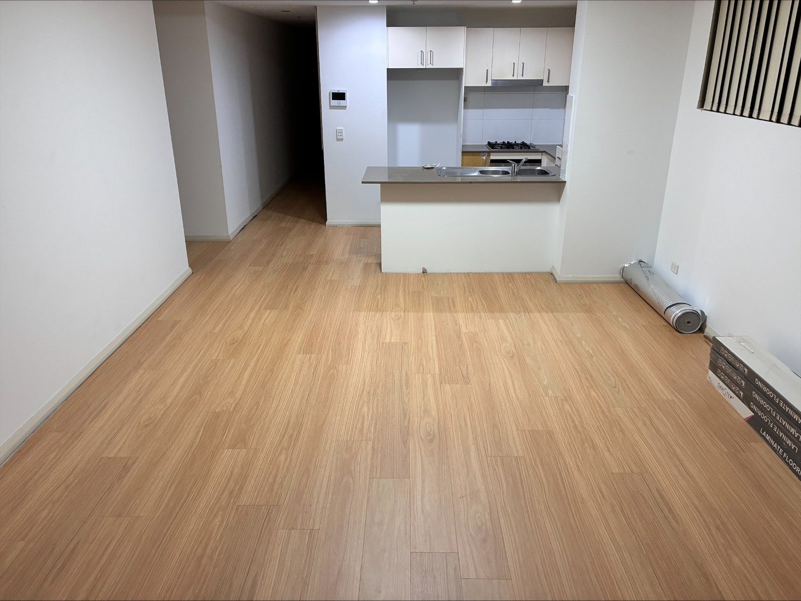 Light timber flooring through an open-plan kitchen and living area